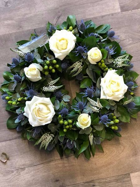 A Classic Wreath including White Roses, Thistle, Hypericum and Veronica funeral tribute. Buy online or call to discuss.